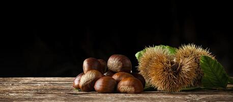 Chestnuts and chestnut bur on wooden table. photo