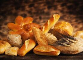 A variety of breads and rolls on a wooden table photo