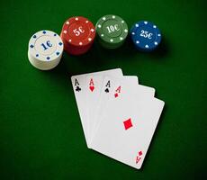 A poker chip, four cards and two chips on a green table photo