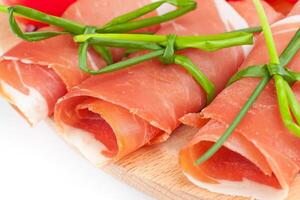 A plate with ham wrapped in bacon and tomatoes photo