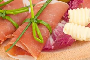A plate with some meat, cheese and vegetables photo