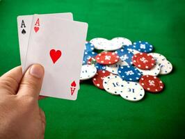 A hand holding two cards and a pile of chips photo