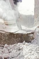 A person is using a hammer to break up a concrete wall photo