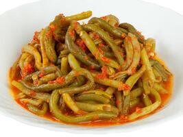 A bowl of green beans with sauce on top photo