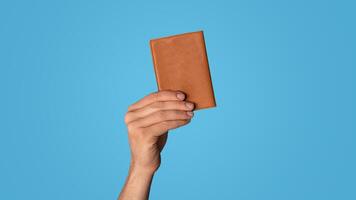 Unrecognizable young guy showing passport on color background, closeup of hand photo
