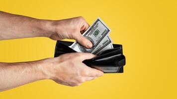Unrecognizable young man taking dollars from wallet on white background, copy space. Panorama photo