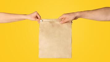 Takeaway food concept. Delivery man giving paper bag with empty space for design to client, orange background photo