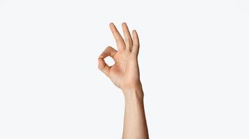 Unrecognizable young man showing okay gesture, expressing agreement on white background, close up view. Panorama photo