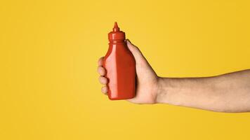 Closeup view of millennial guy showing squeeze bottle of mustard on orange background, mockup for design. Panorama photo