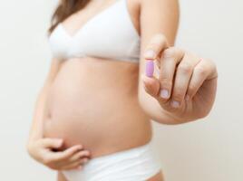 Vitamin pill in the hands of a pregnant woman photo