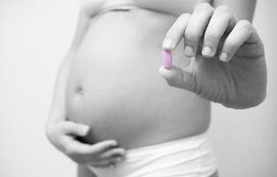Vitamin pill in the hands of a pregnant woman photo