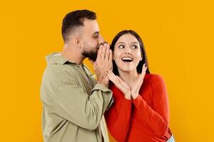 A couple, happily engaged in a playful moment, enjoys each other's company. The man whispers to the woman, who expresses delight, highlighting their love and affection. photo