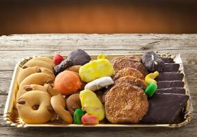 A tray of assorted cookies and candies on a wooden table photo