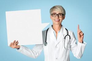 Doctor got an idea, points finger up and holds abstract place for words. On blue background photo