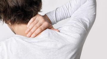Pain in neck from work. Guy presses his hand to sore spot, back, close up, studio shot photo
