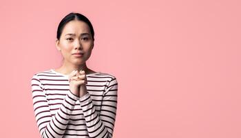 Please. Young asian female begging for something with clasped hands and looking at camera, desperate sad korean woman pleading and asking for help while standing over pink background, copy space photo