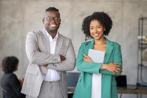 In a contemporary office, a diverse team engages in successful collaboration. Two professionals smile confidently while others participate in a meeting, fostering teamwork and unity. photo