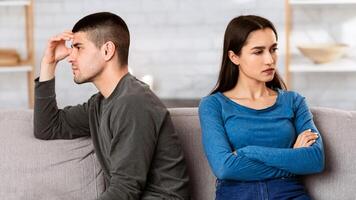 Quarantine Quarrels. Couple ignoring each other after arguing during isolation, sitting apart on sofa in their apartment photo