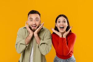 A young married couple expresses excitement, both smiling widely and making playful gestures with their hands. Their vibrant expressions convey love and happiness in a cheerful atmosphere. photo