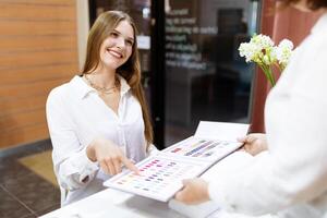 Ladies are enjoying a manicure at a salon, choosing from a variety of vibrant nail polish shades while engaging with attentive staff. A moment of personalized pampering unfolds. photo