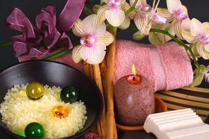A bowl of soap, a towel, a candle, and a pink flower photo