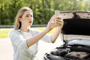Unhappy young blonde woman looking for signal after car accident, holding cellphone, cannot find mobile network, having difficulty calling roadside service. Road problems concept photo