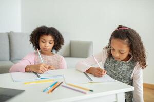Two daughters engage in creative activities at home, drawing and writing with colorful pencils. photo