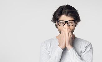 Guy with glasses has headache and rubs nose from fatigue photo
