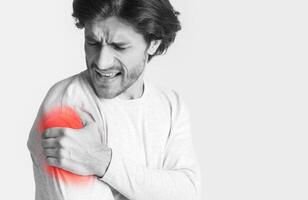Man screams at pain in shoulder. Injury highlighted in red, free space photo