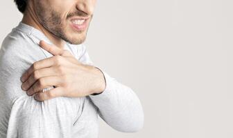Man face expresses pain. Guy has Inflammation in shoulder, empty space photo