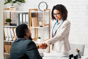 Black hiring manager shaking hands with successful vacancy candidate after work interview at modern office, copy space photo