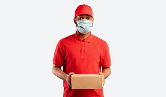 Delivery Service. African Courier Guy Holding Cardboard Box Delivering Parcel Package Wearing Protective Mask Posing Over Yellow Background. Studio Shot photo