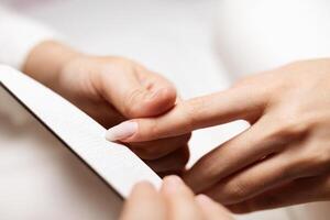 Women are pampering themselves as they receive manicures in a stylish salon. Skilled hands focus on nail care using a file to shape and enhance their appearance. photo