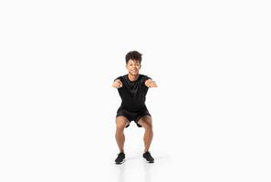 A young Brazilian man is performing a squat exercise, showcasing proper form and focus. He is dressed in athletic wear, emphasizing a commitment to fitness and a healthy lifestyle. photo