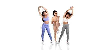 Three women engage in dynamic stretching exercises in a well-lit fitness studio. They wear colorful activewear and display various poses, emphasizing flexibility and strength. photo