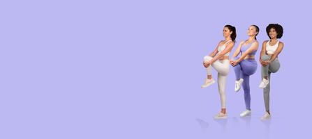 Three women are performing an exercise routine together, showcasing different athletic poses in vibrant workout clothing. They appear focused and energized during their fitness session. photo
