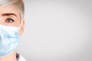 Health and medicine concept. Portrait of friendly therapist in protective mask, close up, isolated on light background, studio shot photo