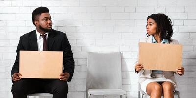 Millennial vacancy applicants with cardboard job searching signs sitting in company hall, waiting for interview photo