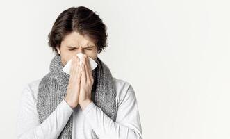 Millennial man with scarf, blows nose in napkin photo