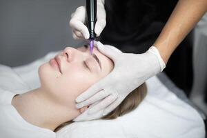 A client relaxes in a modern salon as a technician carefully applies permanent makeup to enhance her eyebrows. The setting promotes beauty and pampering through expert services. photo
