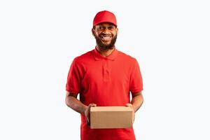 Package Delivery. Black Courier Man In Uniform Holding Cardboard Box Smiling To Camera Over Yellow Background. Studio Shot photo