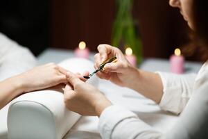 In a relaxing salon setting, a woman enjoys a manicure treatment while having her nails pampered. Soft candlelight creates a serene atmosphere for beauty care. photo