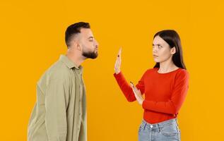 A young couple appears to be engaged in a serious conversation. The woman holds up her hand in a gesture of pause while maintaining eye contact with the man, who listens attentively. photo