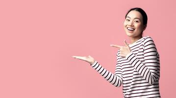Look At This. Positive Young Asian Female Pointing At Her Open Empty Palm, Cheerful Korean Woman Demonstrating Invisible Object, Recommending Something While Posing On Pink Background, Copy Space photo