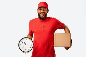 Express Delivery. Joyful Courier Holding Cardboard Box And Clock Delivering In Time Standing Over Yellow Background. Studio Shot photo