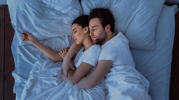 Husband And Wife Hugging Sleeping Together Lying In Bed At Home, Above View Shot. Married Couple Resting In Cozy Bedroom, Embracing And Napping. Happy Marriage Concept photo