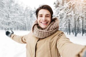 Winter Mood. Happy Man Taking Selfie Standing In Snowy Forest in Morning. Selective Focus photo