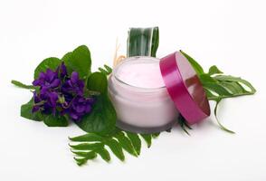 Cosmetic pink cream with herbs and flowers photo