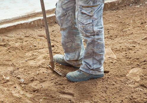 Worker with rake while crushing the ground in the yard photo