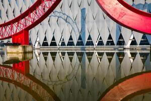 A red bridge with a reflection of a building photo